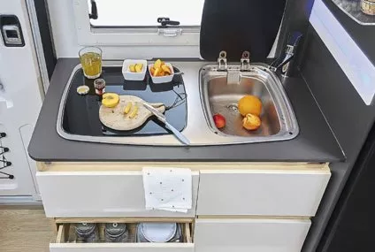 Cuisine compacte de camping-car avec évier, planche à découper et fruits