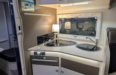Cuisine compacte de camping-car avec évier, plaque de cuisson et éclairage intégré.