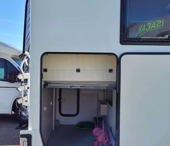 Compartiment de rangement ouvert d'un camping-car sur un parking.