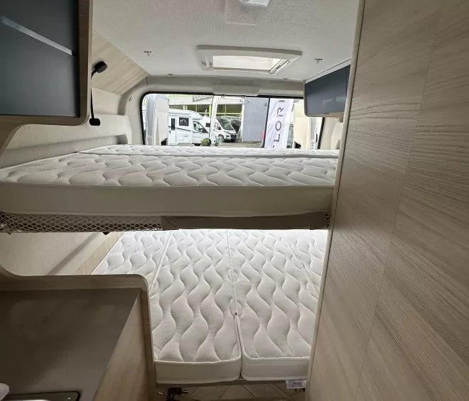 Intérieur d'un camping-car avec lits superposés et kitchenette en bois clair