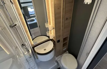 Salle de bain compacte avec lavabo, douche et toilettes dans un camping-car moderne.