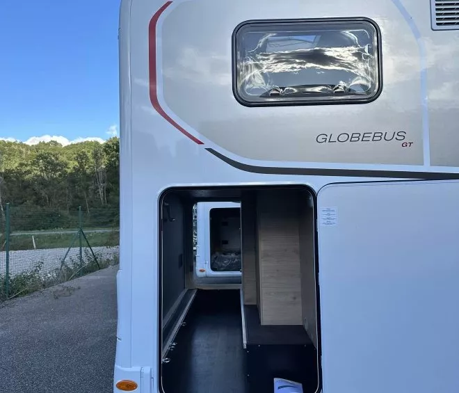 Compartiment de rangement ouvert d'un camping-car Globebus GT sur un parking.