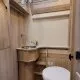 Salle de bain compacte en bois clair avec lavabo et toilettes dans un camping-car.