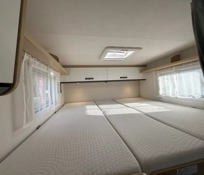 Intérieur d'une caravane avec lits jumeaux et rangements supérieurs