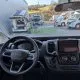 Vue intérieure d'un camping-car Fiat avec tableau de bord et véhicules stationnés à l'extérieur