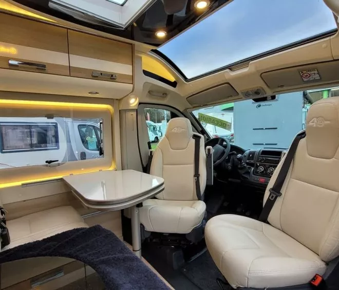 Intérieur d'un camping-car moderne avec sièges en cuir et table pliante.