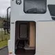 Compartiment de rangement ouvert à l'arrière d'un camping-car sous ciel nuageux
