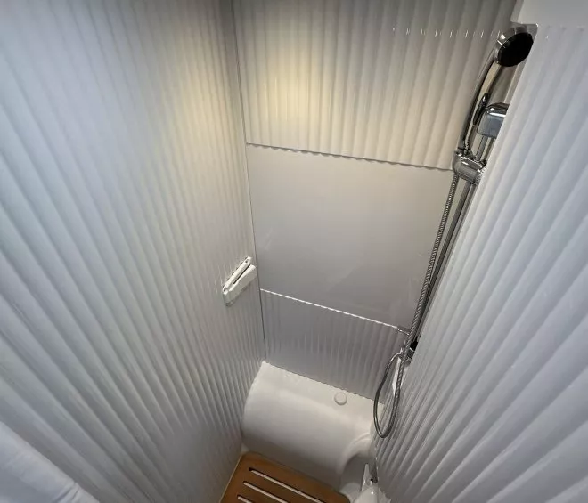 Douche compacte avec parois blanches et sol en bois, éclairage intégré