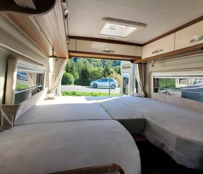 Intérieur d'un camping-car avec lit double et vue sur la route
