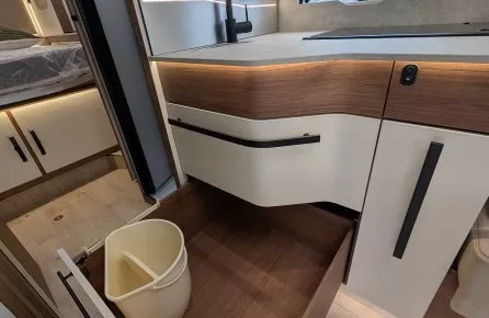 Cuisine moderne de camping-car avec évier, tiroir ouvert et poubelle intégrée