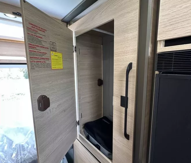 Intérieur d'un placard en bois clair avec porte ouverte dans un camping-car moderne.