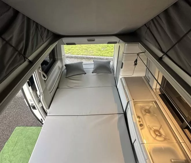 Intérieur d'un van aménagé avec lit déplié et kitchenette moderne