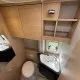 Salle de bain compacte en bois clair avec lavabo et toilettes dans un camping-car moderne.