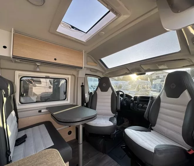 Intérieur d'un camping-car moderne avec sièges et table, éclairage naturel.