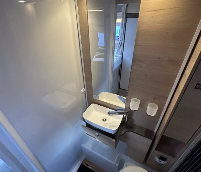Salle de bain compacte avec lavabo, miroir et toilettes dans un camping-car moderne.