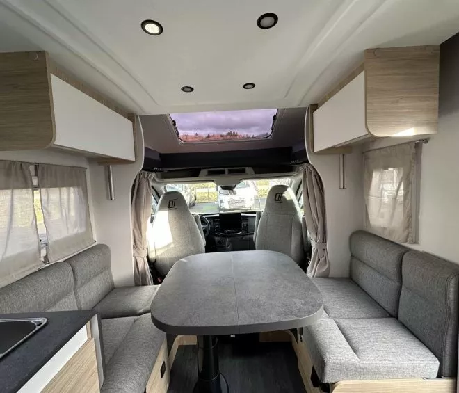 Intérieur d'un camping-car moderne avec table et banquettes grises