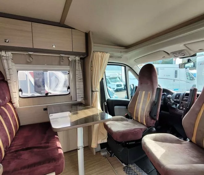 Intérieur d'un camping-car avec sièges et table, ambiance confortable.