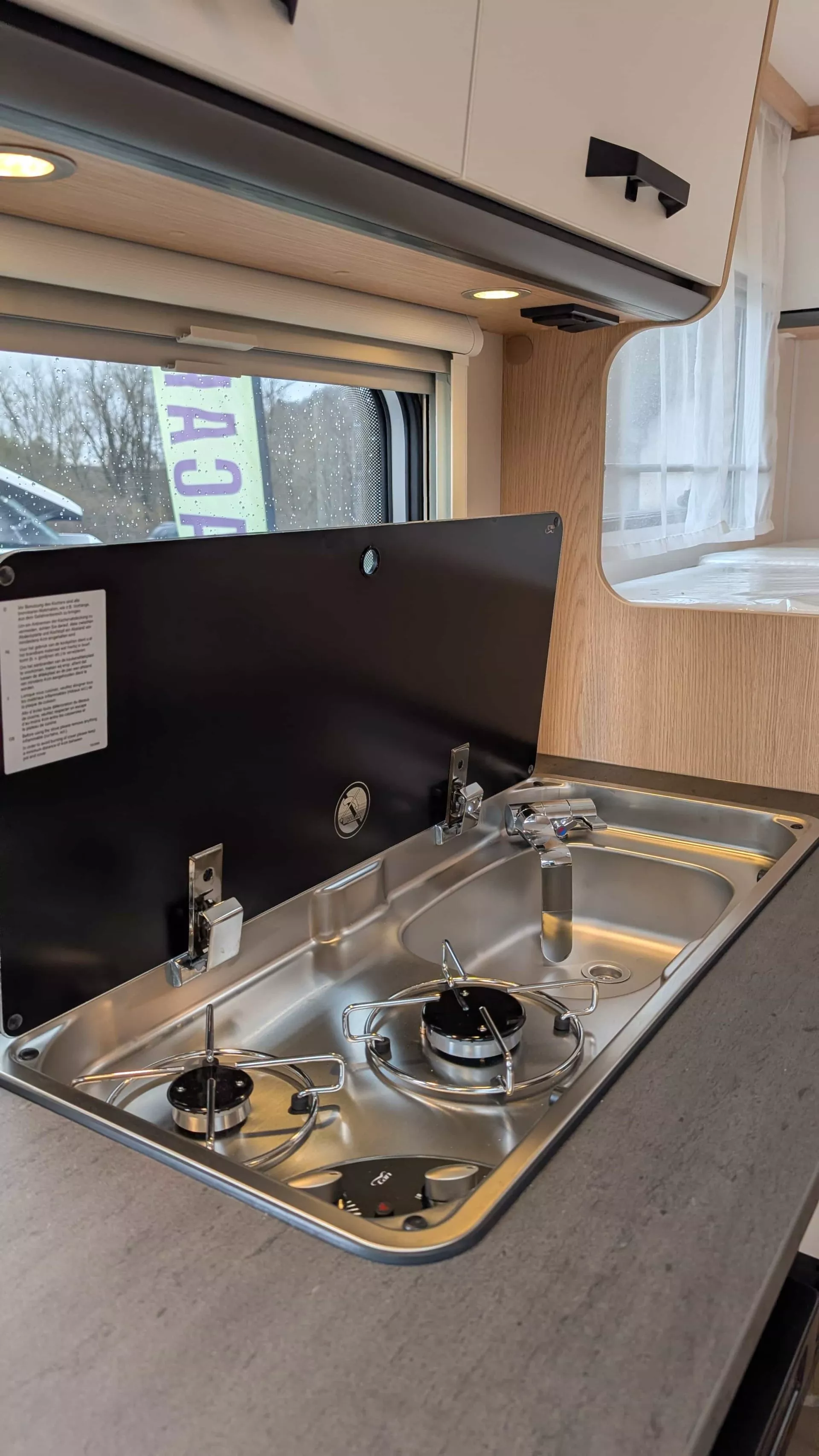 Cuisine intégrée avec plaques de cuisson et évier dans un camping-car moderne.