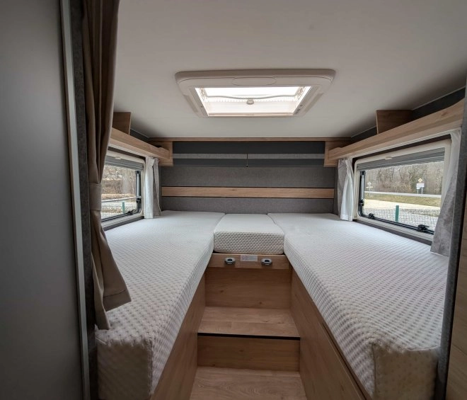 Intérieur d'une caravane avec deux lits simples et fenêtres latérales