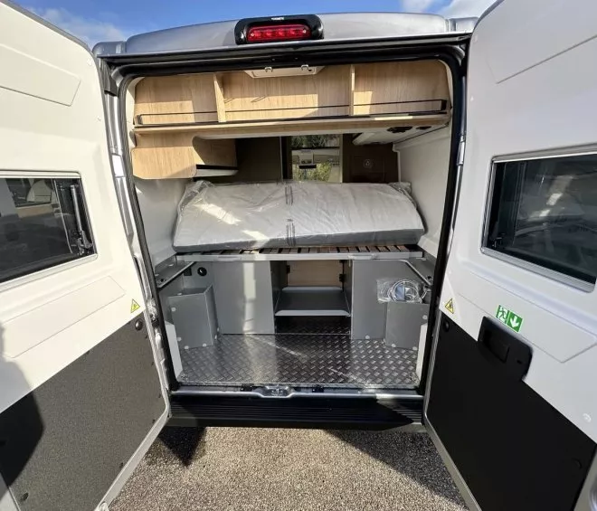 Intérieur d'un van aménagé avec lit et rangements en bois clair.