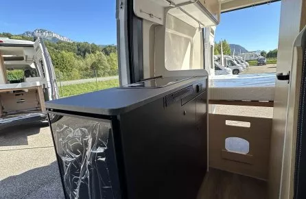 Intérieur d'un van aménagé avec vue sur l'extérieur et rangements intégrés