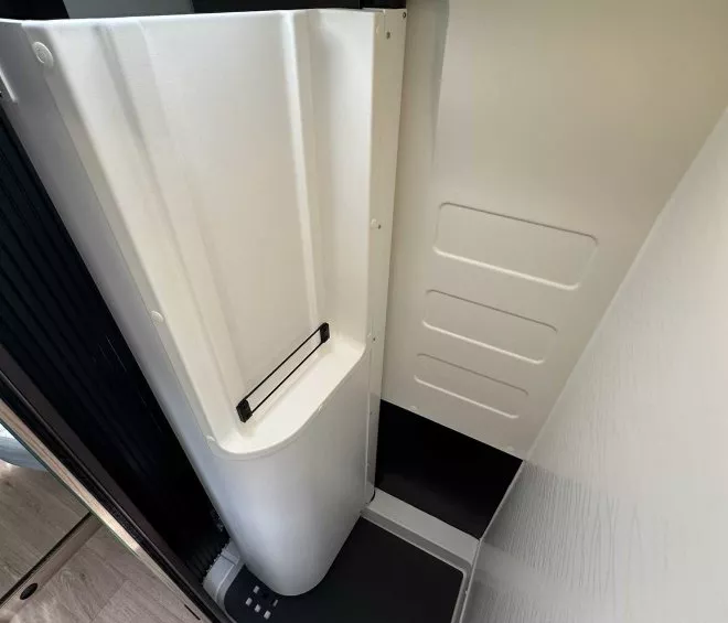 Douche compacte moderne dans un espace restreint avec parois blanches et sol antidérapant.