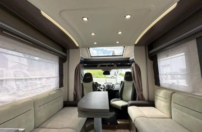 Intérieur spacieux d'un camping-car moderne avec sièges et table.