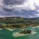 Paysage de lac entouré de forêts sous un ciel nuageux, région montagneuse.