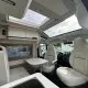 Intérieur d'un camping-car moderne avec sièges en cuir et toit panoramique.