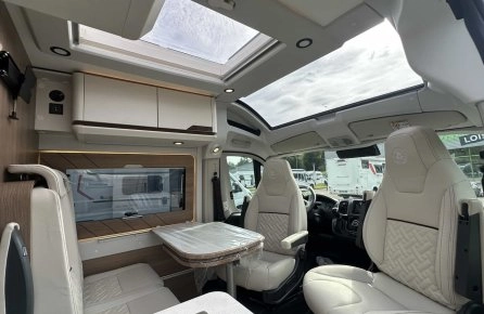 Intérieur d'un camping-car moderne avec sièges en cuir et toit panoramique.