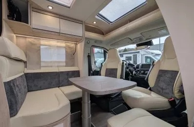 Intérieur d'un camping-car moderne avec sièges en cuir beige et table centrale.