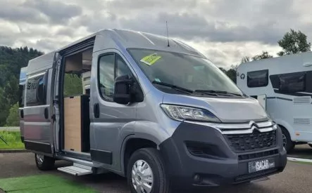 Fourgon aménagé Citroën gris stationné sur un parking, porte latérale ouverte