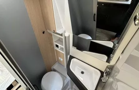 Salle de bain compacte dans un camping-car moderne avec lavabo et toilettes.