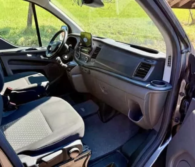 Intérieur d'un véhicule utilitaire moderne avec sièges avant et tableau de bord visible.