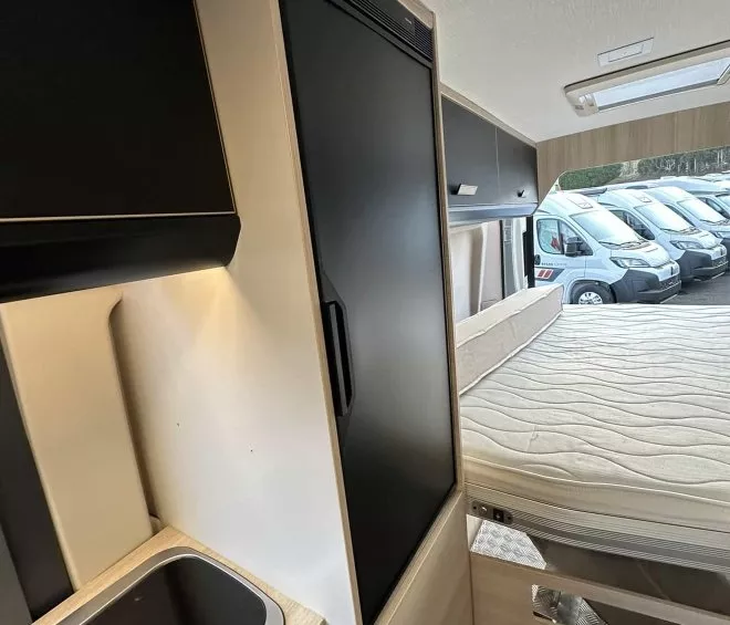 Intérieur d'un camping-car avec lit, kitchenette et rangements modernes.
