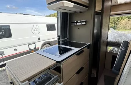 Intérieur moderne d'un camping-car avec cuisine équipée et rangements en bois clair.