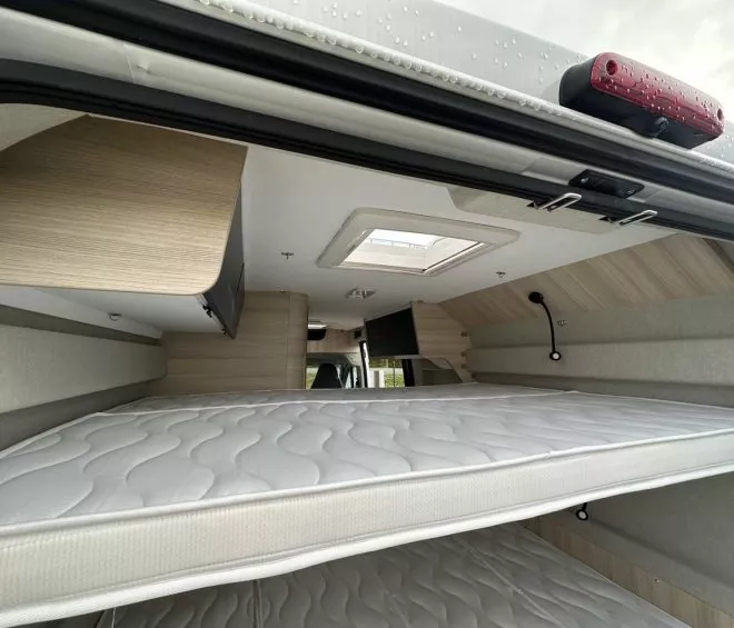Intérieur d'un camping-car avec lits superposés et rangement en bois clair