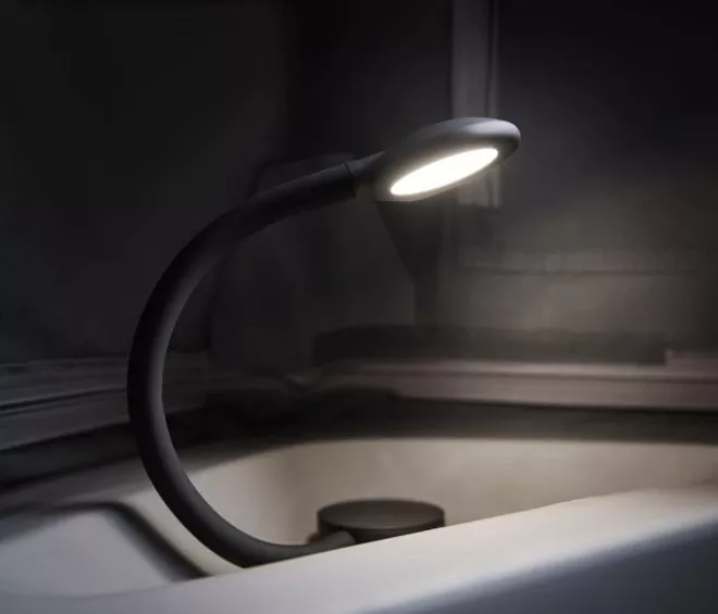 Lampe flexible allumée dans un environnement sombre, éclairant un espace intérieur.