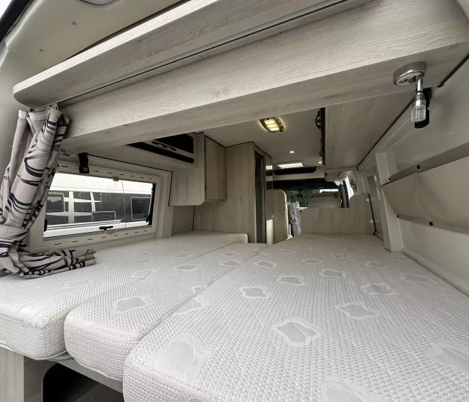 Intérieur d'un van aménagé avec lit et rangements en bois clair