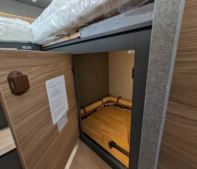 Rangement sous un lit dans un camping-car moderne avec matelas emballé.