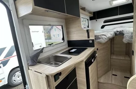 Intérieur moderne d'un camping-car avec cuisine équipée et rangements en bois clair.