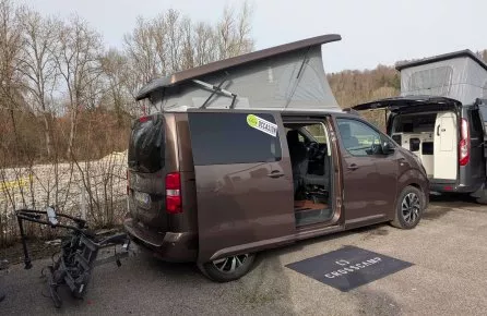 Véhicule Crosscamp marron avec toit relevable et porte ouverte, stationné en extérieur.