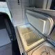 Intérieur d'un van aménagé avec réfrigérateur ouvert et évier intégré.