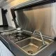 Cuisine compacte avec évier et plaque de cuisson intégrés dans un véhicule aménagé.