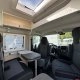 Intérieur d'un camping-car moderne avec sièges et table pliante.