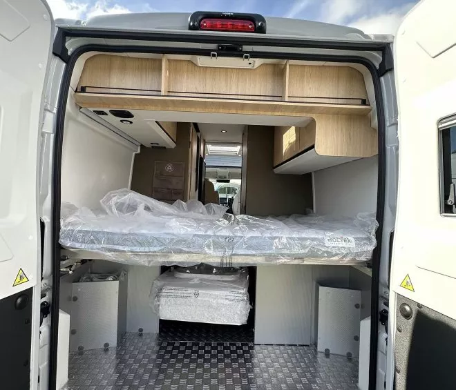 Intérieur d'un fourgon aménagé avec lit et rangements en bois