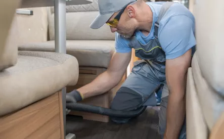 Technicien nettoyant l'intérieur d'un camping-car avec un aspirateur