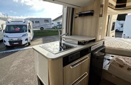 Intérieur d'un camping-car moderne avec cuisine équipée et espace de couchage.