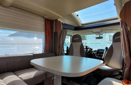 Intérieur d'un camping-car avec table et sièges en cuir, lumière naturelle.