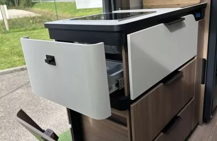 Cuisine compacte intégrée dans un van aménagé avec évier et rangements ouverts